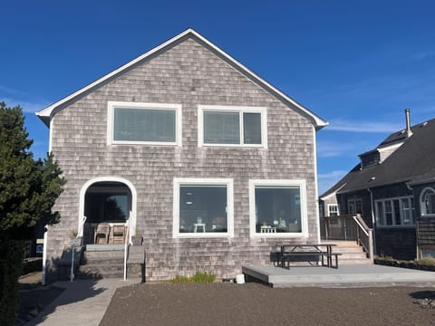 Modern beach house exterior featuring clean architectural lines and natural shingle siding, located in a quiet residential neighborhood just steps from the shore.
