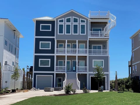 This stunning four-story coastal property features bright white trim against charcoal siding and multiple private balconies. The rooftop deck and elevated design promise ocean breezes and memorable sunsets nearby.
