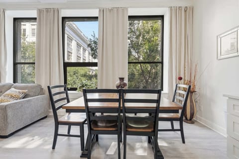 Dining Room | Cozy dining area with a wood table for six, set beneath tall windows with tree-lined 4th street city views.
