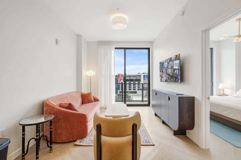 Bright and modern living room with a cozy sofa and stunning city views, perfect for relaxation.