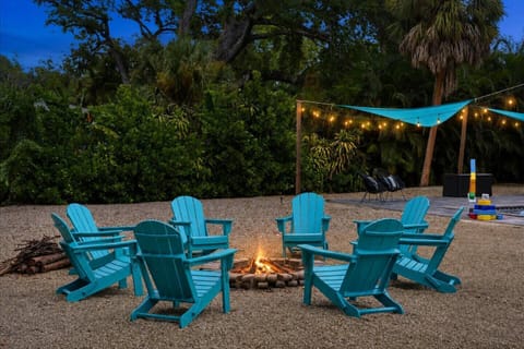 Gather around the glowing fire pit beneath the twilight sky. Surrounded by colorful Adirondack chairs, tropical greenery and warm string lights, this inviting backyard setting is perfect for conversation, s’mores and memorable evenings together.
