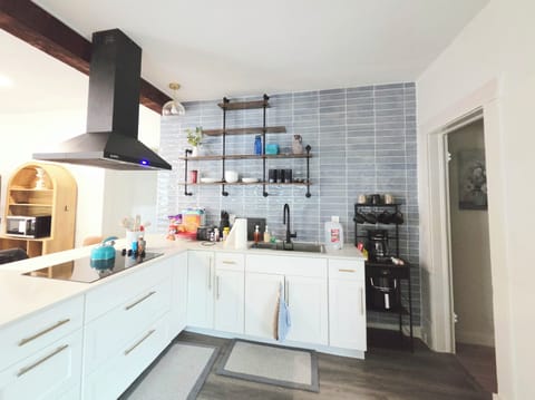 Bright modern kitchen with stylish tile, open shelving, and coffee station