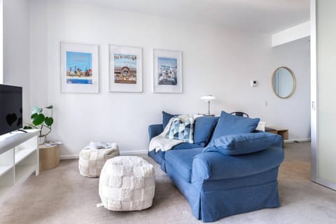 Sink into the plush blue sofa in the air-conditioned living area, where calming tones and curated artwork offer a relaxed city retreat.