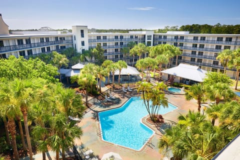 Outdoor pool surrounded by palm trees and lounge chairs.