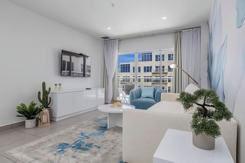 Modern oceanfront property features a pristine pool deck with stunning turquoise waters stretching to the horizon beyond adjacent buildings and manicured grounds.