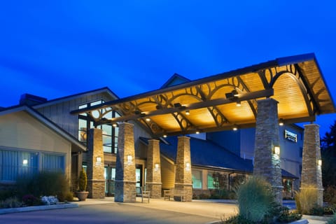 A wood canopy and stone pillars mark the entrance, lit for evening arrivals