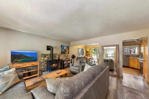 Wall-mounted flat mirror with a natural wood frame reflects light from the living area into the kitchen with oak cabinets and stainless appliances.