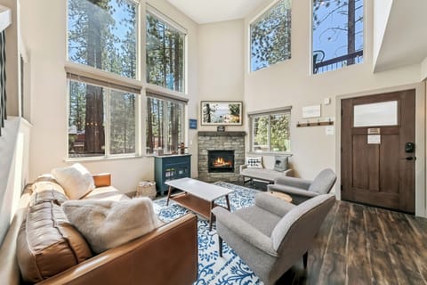 Relax in your bright living room where soaring ceilings and floor-to-ceiling windows frame stunning forest views. The cozy fireplace creates the perfect ambiance after a day of mountain adventures.