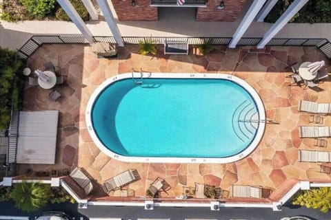 Shared outdoor area with a communal pool, lounge chairs, dining tables, and BBQ grill.