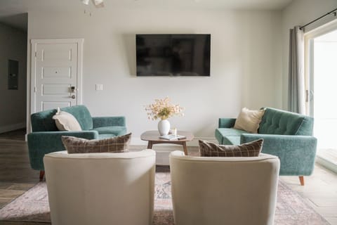 Bright, stylish living room with cozy seating and wall-mounted TV