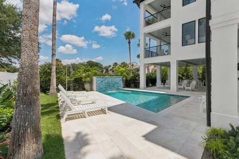 Your private oasis awaits under sunny skies—unwind by the shimmering pool surrounded by lush tropical palms and modern elegance.