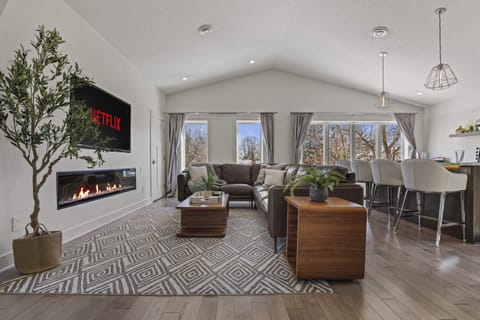 Open concept living area with high end leather couch, gas fire place, and 65" smart TV.