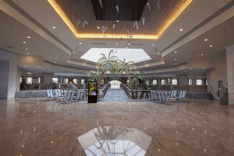 Step into a grand atrium beneath glowing skylight and palms.