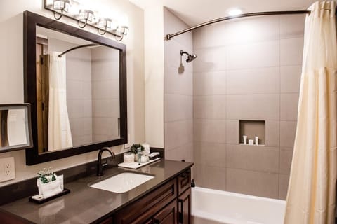 Bright modern bathroom with tiled tub-shower and stylish dark wood vanity