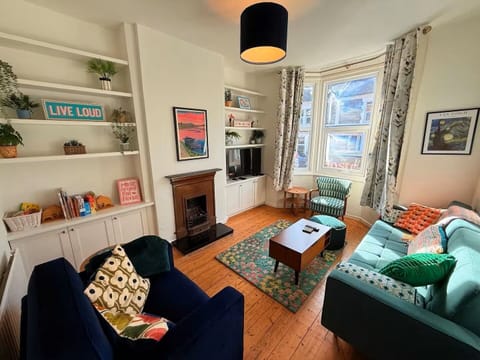 The vibrant living room features a comfortable double sofa bed and a smart TV