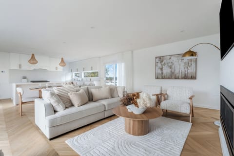 Gather in the main living area where plush seating, coastal-inspired furnishings, a gas fireplace and open-plan design create an inviting setting for shared evenings.