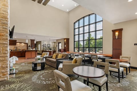 Floor-to-ceiling arched windows flood the two-story lobby lounge with natural light near the breakfast bar.