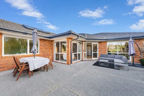 Generous outdoor entertaining area with dining furniture, patio umbrellas and comfortable lounge seating overlooking the garden.