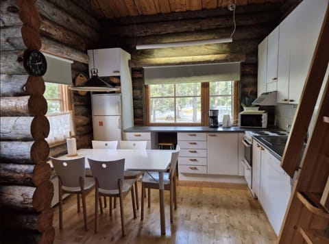 Dining table with chairs in the open-plan kitchen, with a refrigerator, coffee maker and microwave.