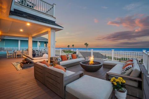Relax on the spacious outdoor deck with cushioned seating, a fire table, and sweeping Gulf views in a peaceful beachfront setting.