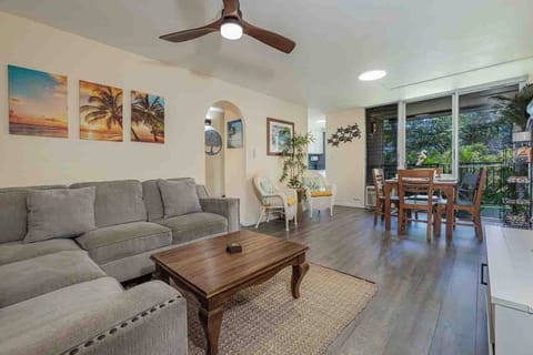 Relax in your spacious living area with plush seating, tropical accents, and direct access to your private balcony overlooking lush greenery.