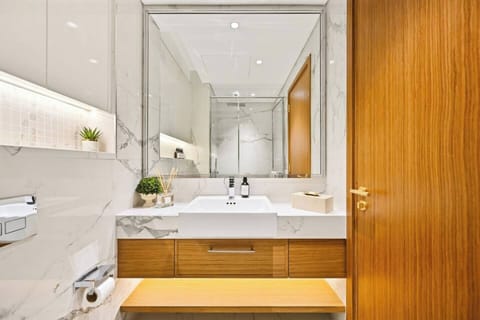 Elegant marble bathroom with warm wooden details, large mirror, soft lighting, and premium toiletries — offering a refined and relaxing space for your daily routine.
