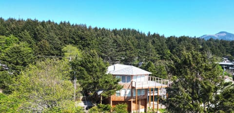 Coastal retreat nestled among lush evergreens with mountain views in the distance. The property offers a peaceful setting surrounded by natural beauty and neighboring homes.