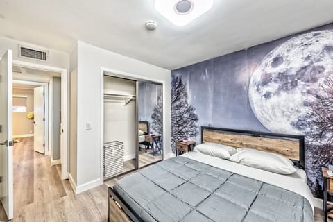 Cozy bedroom with moon mural, queen bed, and mirrored closet