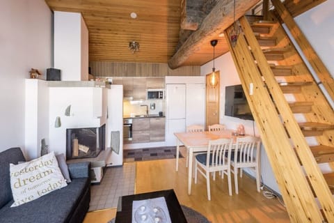 Open-plan living and dining area with a fireplace, sofa, dining table for four, and stairs leading up to the loft.