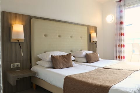 Two beds with pillows and bedside lamps.