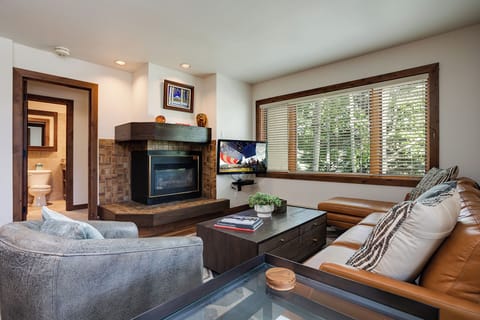 Sink into plush seating by the fireplace, where warm wood tones and natural light create your perfect mountain retreat for relaxation and connection.