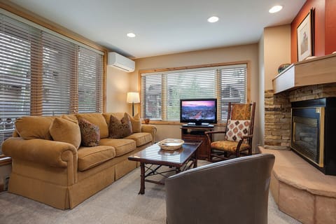 Sink into plush seating by your cozy fireplace, where warm tones and mountain views through large windows create your perfect retreat after a day of adventure.