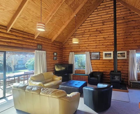 Relax in the spacious living area, featuring comfortable sofas, warm timber interiors and a cosy wood-burning fireplace — the perfect place to unwind, gather together and enjoy peaceful evenings after exploring Cromwell