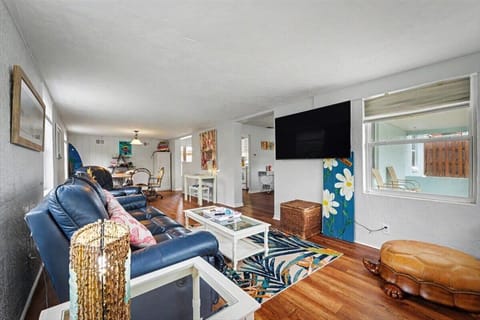 Living room with sectional sofa, wall-mounted TV and wood floors