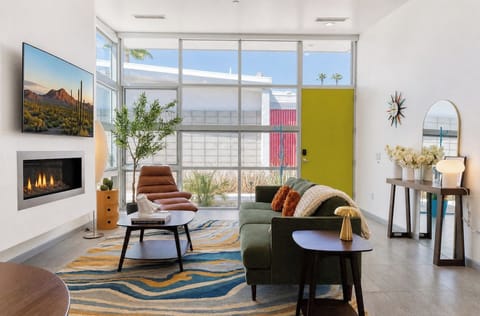 Unwind in your stylish living room featuring a cozy fireplace, plush seating, and floor-to-ceiling windows that flood the space with warm desert light and refreshing views.