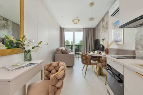 A bright living room with a sofa, armchair, dining area, and large windows.