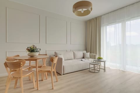 Salon stanowi komfortową przestrzeń do wypoczynku i wspólnego spędzania czasu. Znajduje się w nim wygodna rozkładana sofa, telewizor Smart TV z dostępem do kanałów kablowych oraz część jadalniana ze stołem i krzesłami.