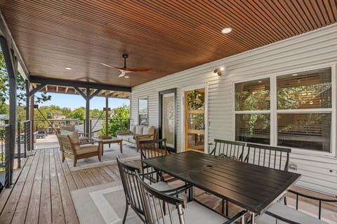 Spacious covered porch with dining table, lounge seating, and fan