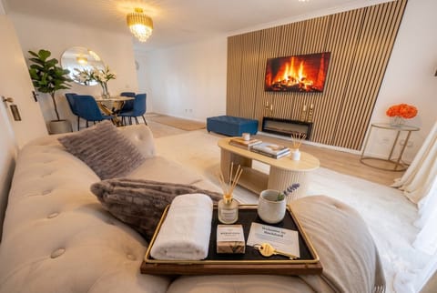 The lounge sofa faces the electric fireplace beneath the slatted wood wall.