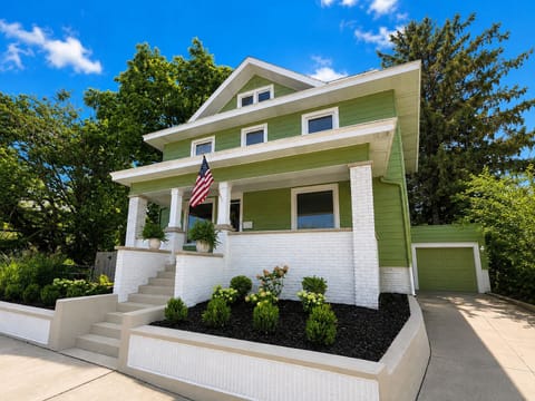 Charming home with welcoming porch, lush landscaping, and private garage