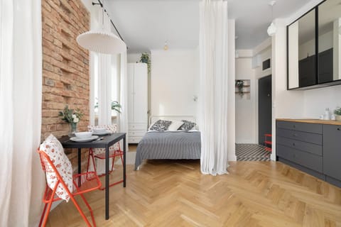 A bright open-plan room with a dining table, bed, and modern kitchen area.