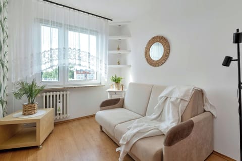 A bright bedroom with a comfortable sofa, armchairs, a floor lamp, and large windows letting in plenty of natural light.