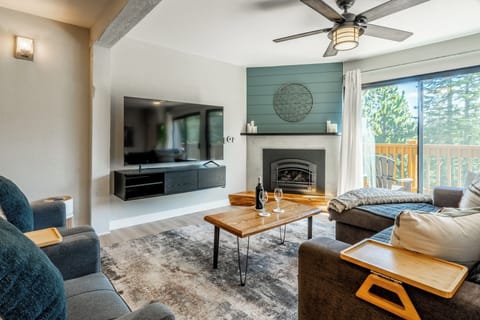 Relax in your cozy living room with mountain views through the sliding glass door. Gather by the fireplace, unwind on plush seating, and enjoy evenings beneath the rustic beam and cooling ceiling fan.