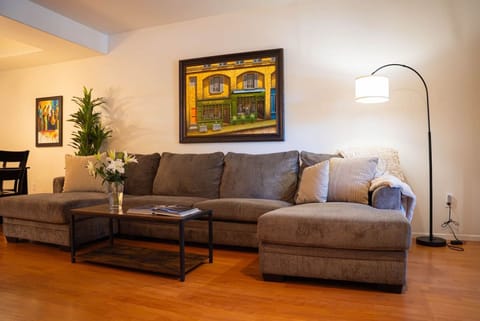 Deep gray sectional facing a mounted TV and sound bar, with a fireplace in a marble surround alongside it