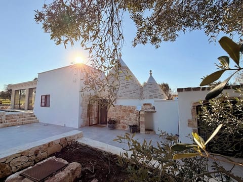 Trullo exterior with stone cones and terrace in afternoon sun
