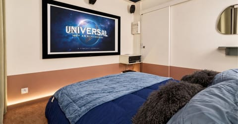 Chambre cinéma — grand écran de projection, ciel étoilé et lit double
