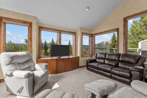 Sink into plush leather seating and let your gaze drift across stunning mountain and forest views through expansive windows—this sun-filled living room becomes your personal sanctuary for relaxation and connection with nature.