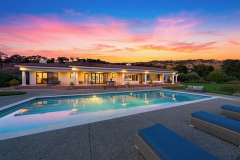 The estate at twilight, pool glowing and hills fading to gold. This is your arrival view.