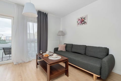 The spacious living room features a comfortable dark grey sofa and a wooden coffee table.