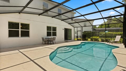 Screened-in private pool area featuring comfortable sun loungers and an outdoor patio dining set.